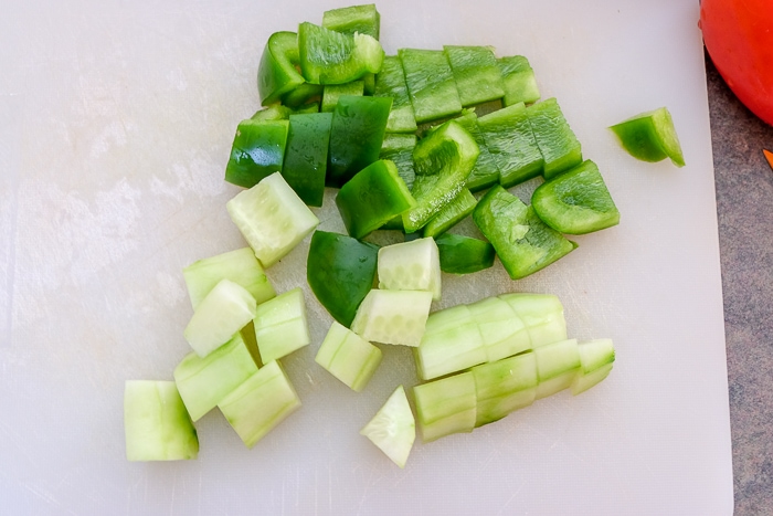 chopped cucumber and green pepper on white cutting board