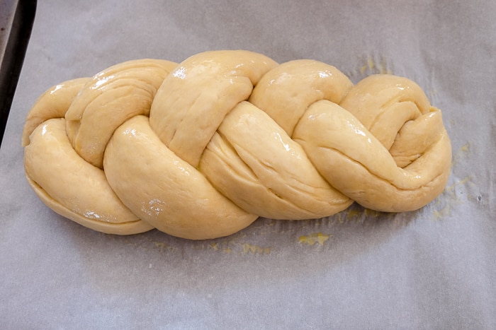 german braided sweet bread covered in egg wash on parchment paper