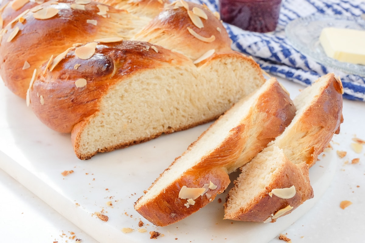 sliced german sweet bread on white marble board with jam behind