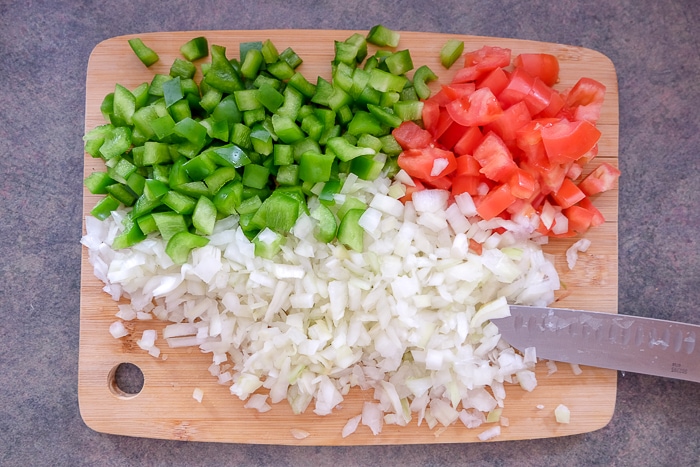 chopped onion pepper and tomato on wooden cutting board