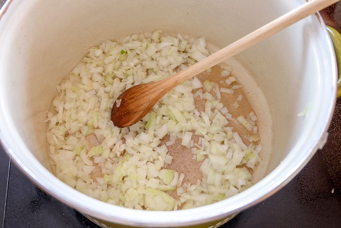 onions frying in large pot with wooden spoon