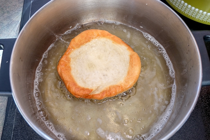 langos dough frying in pot of oil on stove