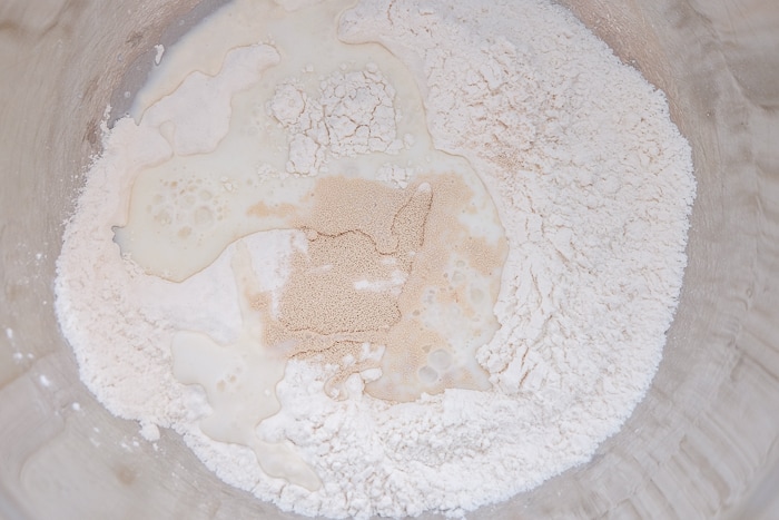 water and yeast with flour in metal mixing bowl