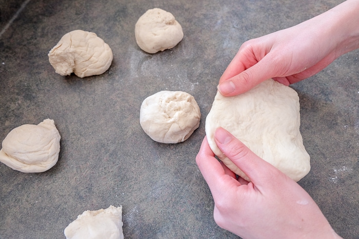 pieces of dough on counter formed flat in pair of hands
