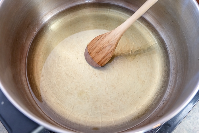 wooden spoon in pot of hot oil on stove