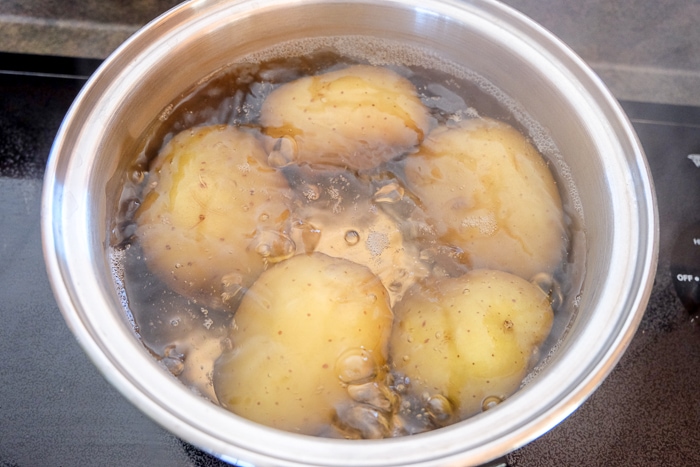 potatoes in boiling water on stove in metal pot