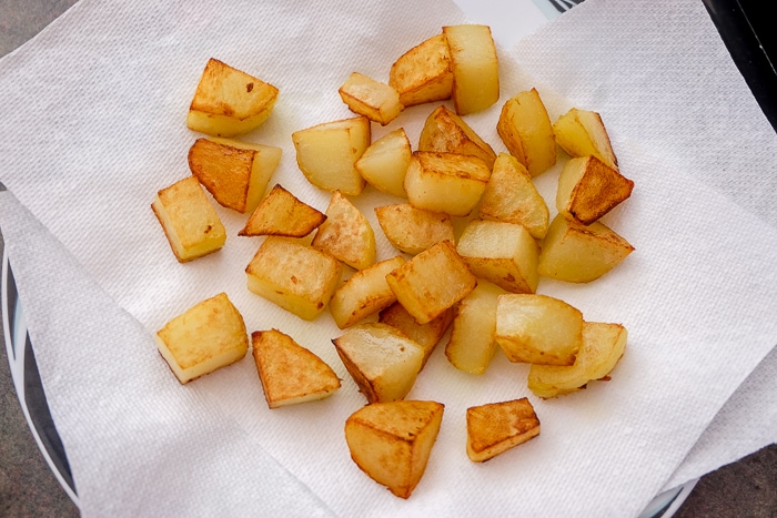 pieces of fried potatoes on paper towels on plate