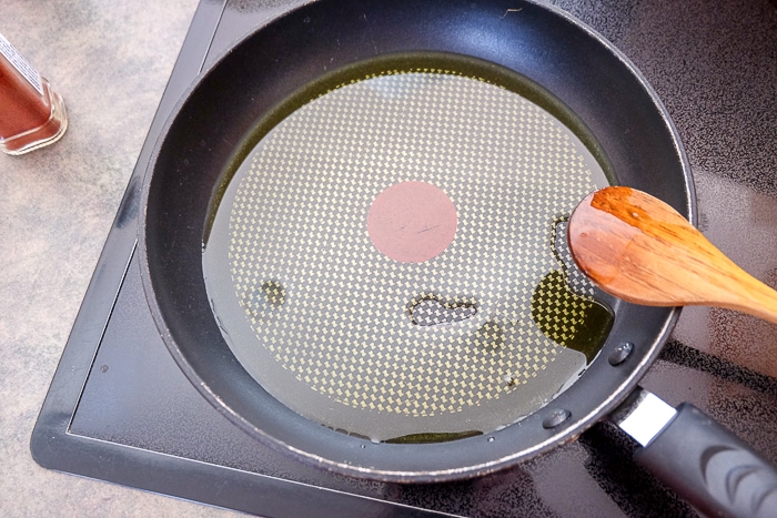 pan of oil on stove with wooden spoon beside