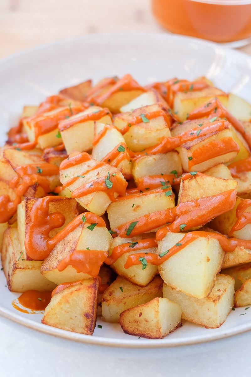 fried potatoes with red bravas sauce in bowl on white counter
