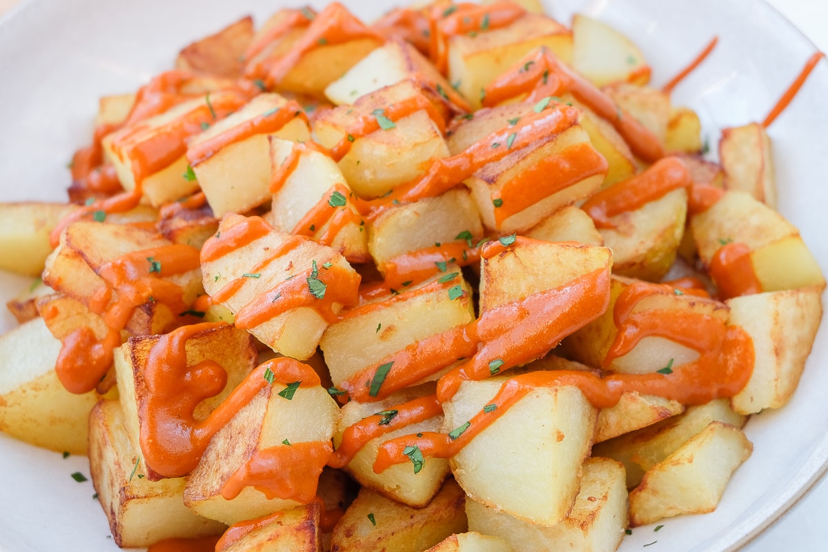 spanish fried potatoes with red sauce in grey bowl