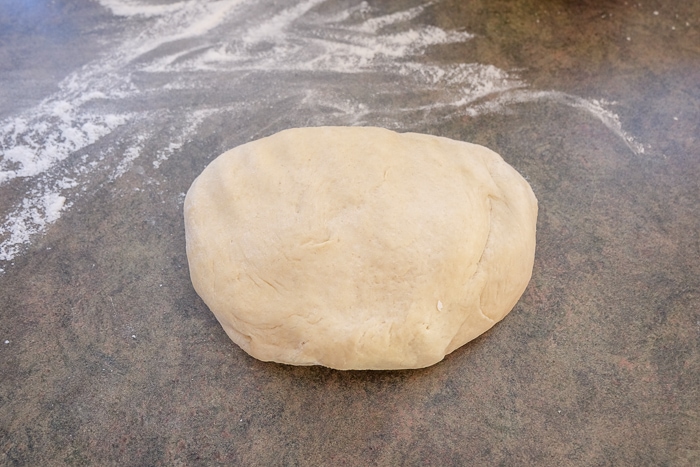 ball of pudding cake dough on counter with flour around