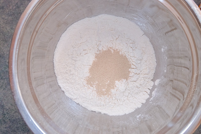 yeast and flour in silver mixing bowl on counter