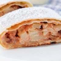 slice of apple strudel topped with powdered sugar on white marble
