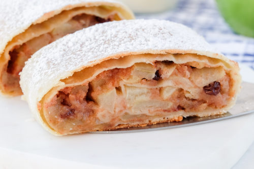 slice of apple strudel topped with powdered sugar on white marble