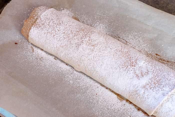 apple strudel dusted with powdered sugar on parchment paper