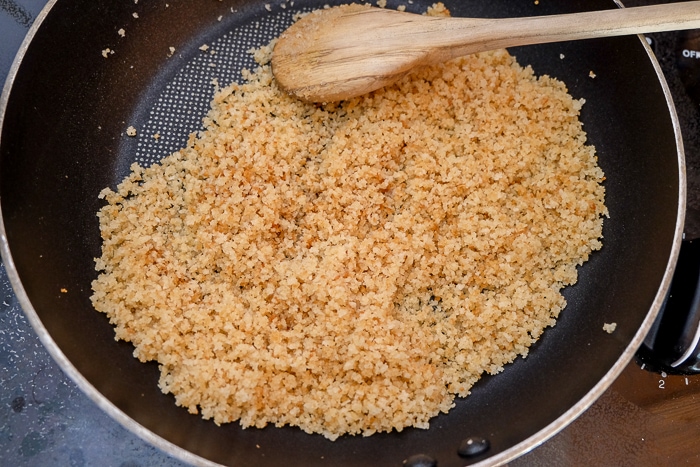 toasted breadcrumbs in frying pan toasted with wooden spoon