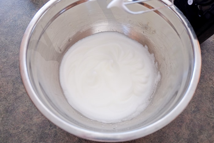 whipped egg whites in silver mixing bowl on counter