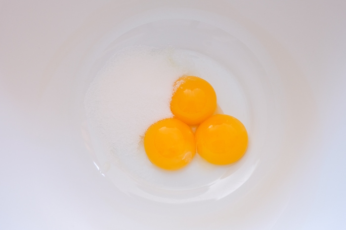 egg yolks in white bowl with sugar