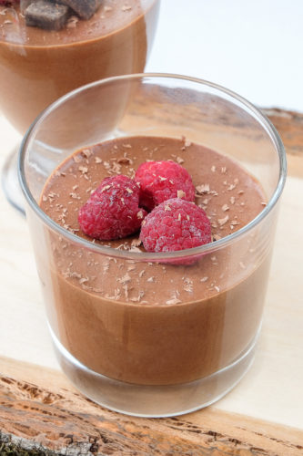 chocolate mousse in glasses on wooden board with berries and chocolate on top