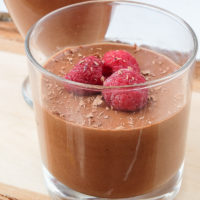 chocolate mousse with raspberries in glasses on wooden board