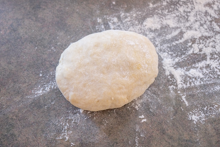 ball of flammkuchen dough on counter in flour