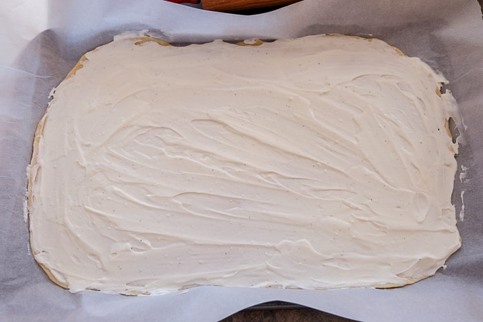 creamy white sauce spread out on flammkuchen dough on pan