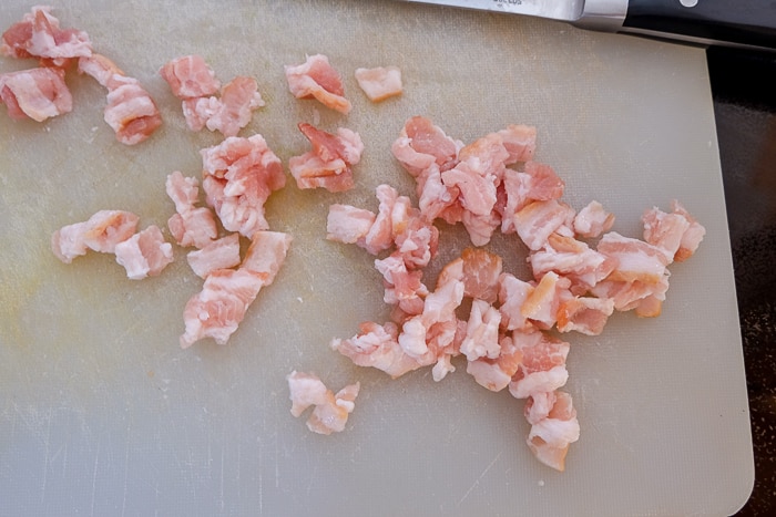 small pieces of bacon cut up on plastic cutting board