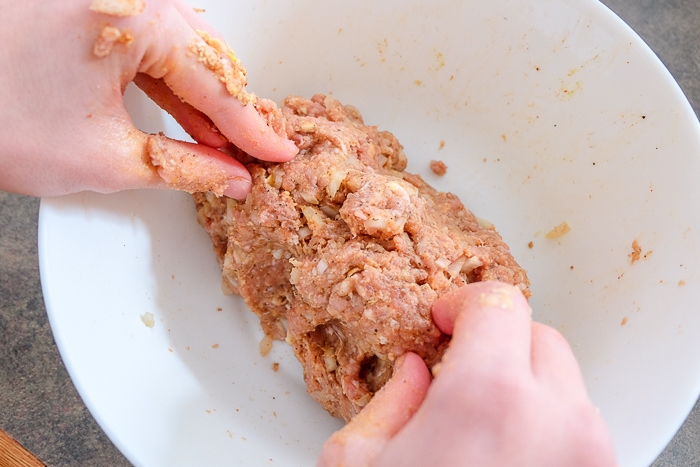minced meat for meatballs mixing in hands in bowl