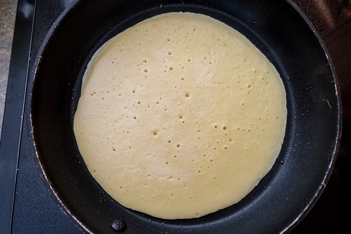 german pancake cooking in black frying pan
