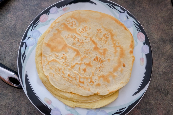 stacked pancakes on plate on counter top