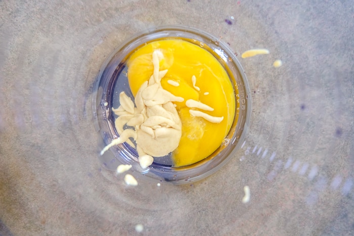 mustard and yolk in mixing container on counter