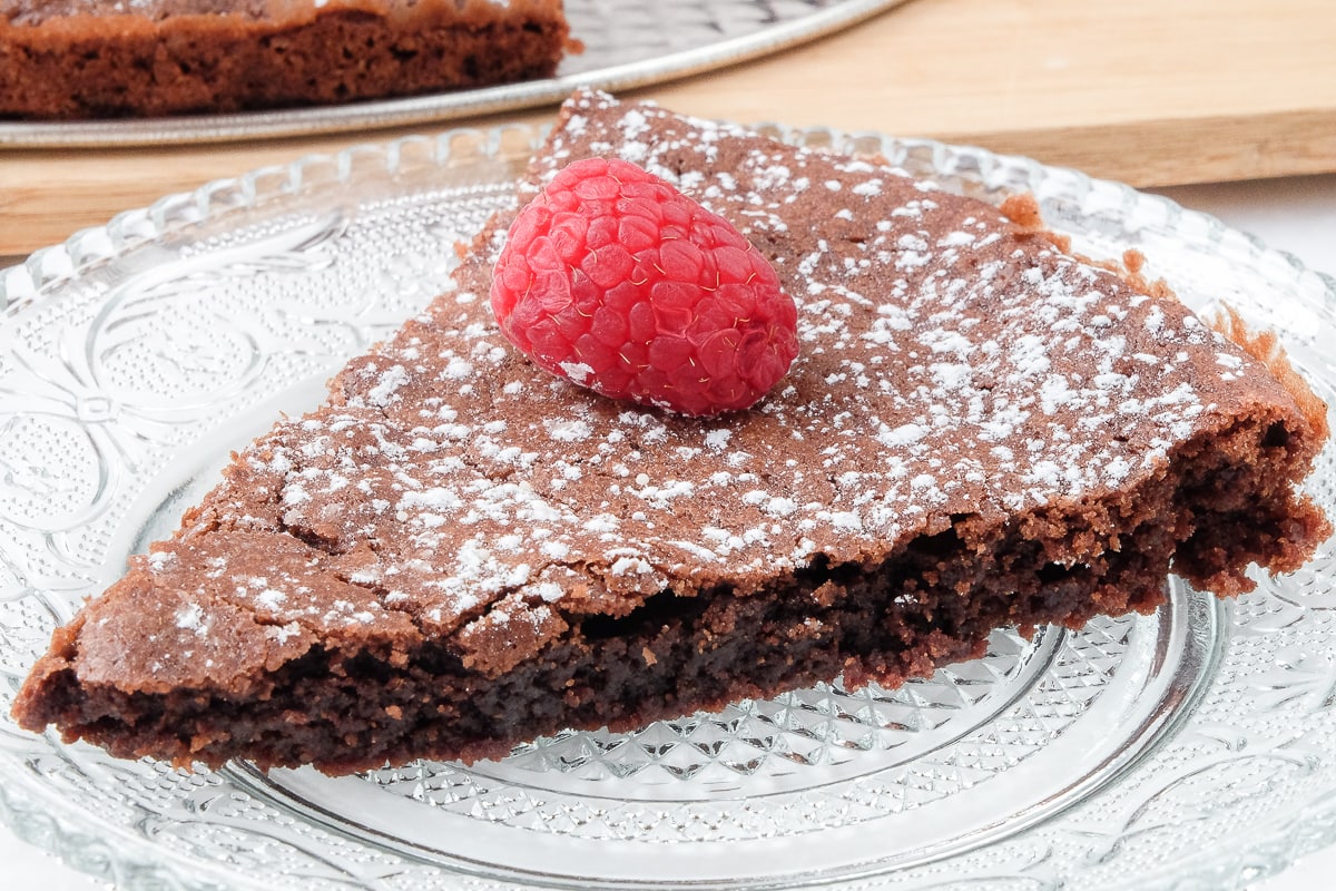 piece of swedish chocolate cake on clear plate with raspberry on top