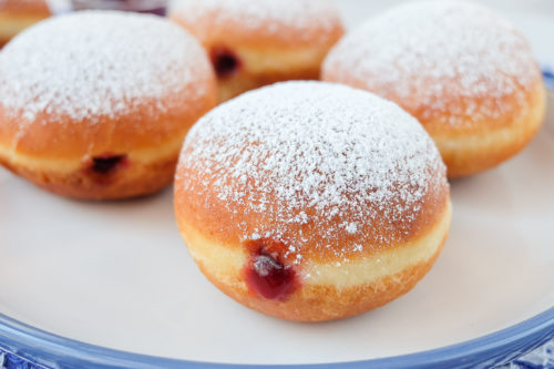 krapfen jelly filled donuts on blue and white plate with powdered sugar on top