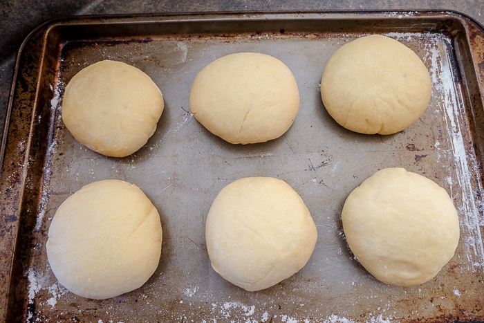 six balls of risen krapfen dough on baking sheet