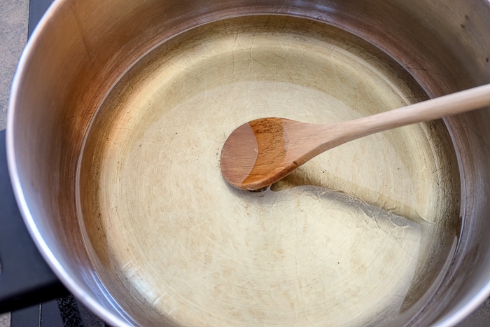 wooden spoon in hot pot of oil on stove top