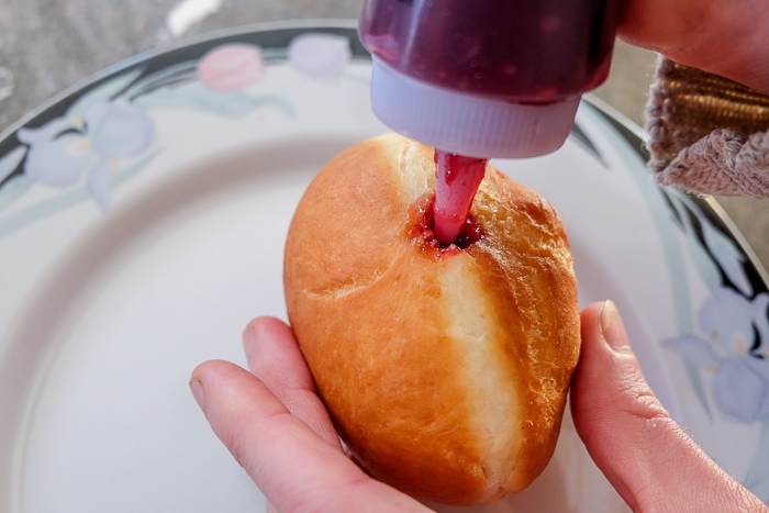 filling donut with red jam from squeeze bottle