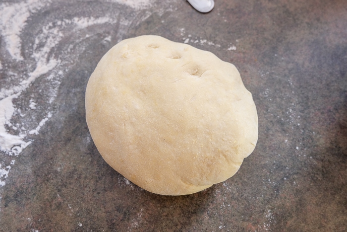 ball of risen krapfen dough on counter with flour