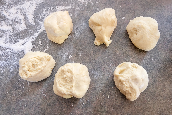 six smaller pieces of ripped dough on counter top