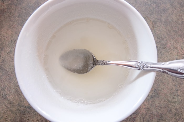 gelatin prepared in white bowl on counter with silver spoon