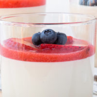 glass of panna cotta with berries and red puree on top