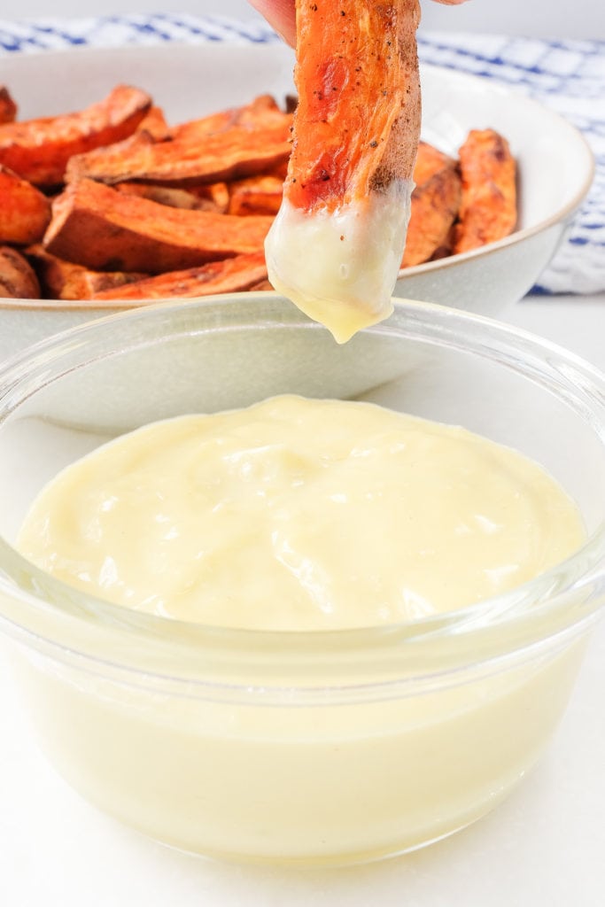 glass dish of homemade aioli with sweet potato fry dipping into it