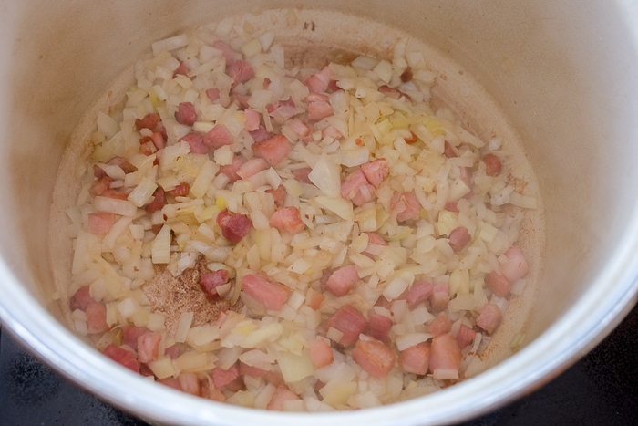 chopped onions and pancetta bacon in bottom of pot on stove