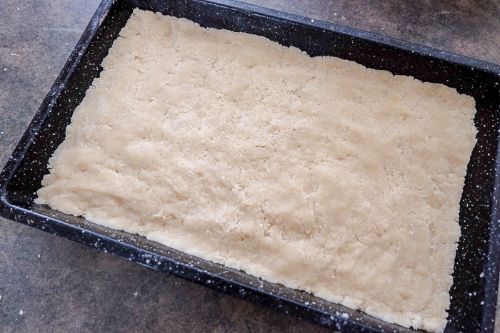shortbread packed down into baking pan on counter