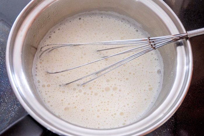 bubbling milk with semolina in silver pot on stove top