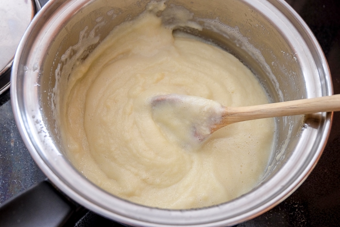 semolina pudding stirred in pot with wooden spoon