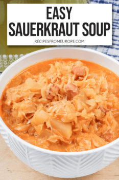 sauerkraut soup with orange broth in white bowl on wooden board with text overlay saying "easy sauerkraut soup"