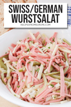 strips of sausage, cheese and pickles made into salad in white bowl with text overlay saying "Swiss / German Wurstsalat"