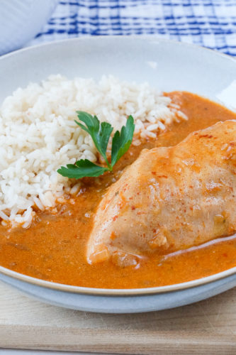 chicken paprikash with rice in bowl with blue towel behind