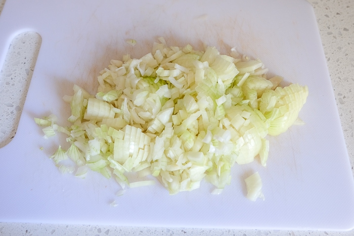 chopped onions on white cutting board on counter