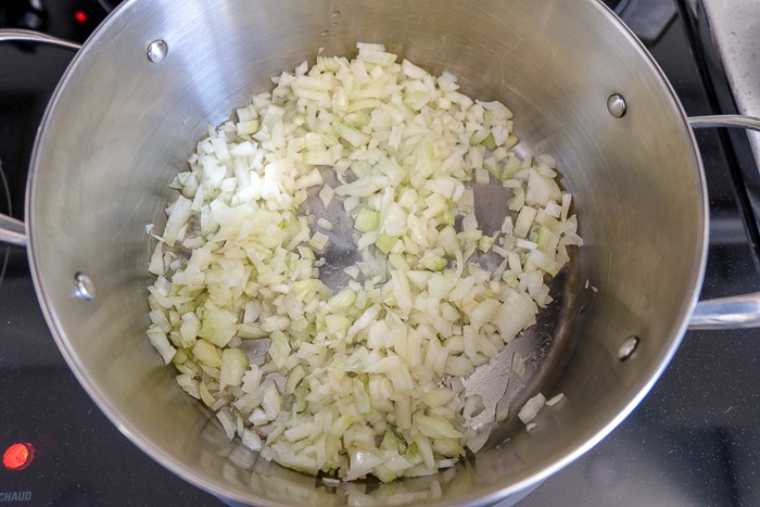 chopped onions cooking in silver pot on stove top